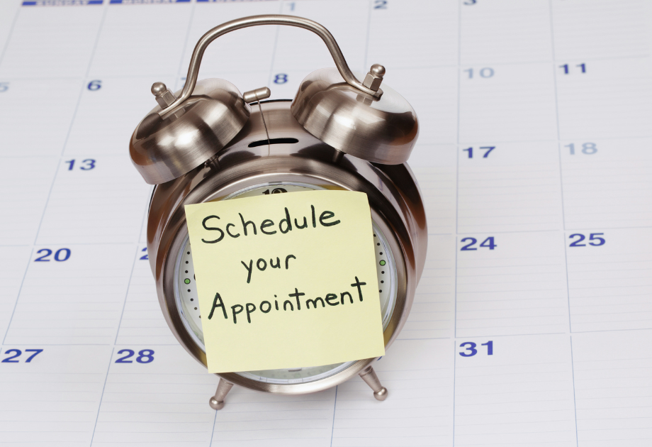 Alarm clock with a note reading “Schedule your Appointment” placed on a calendar.